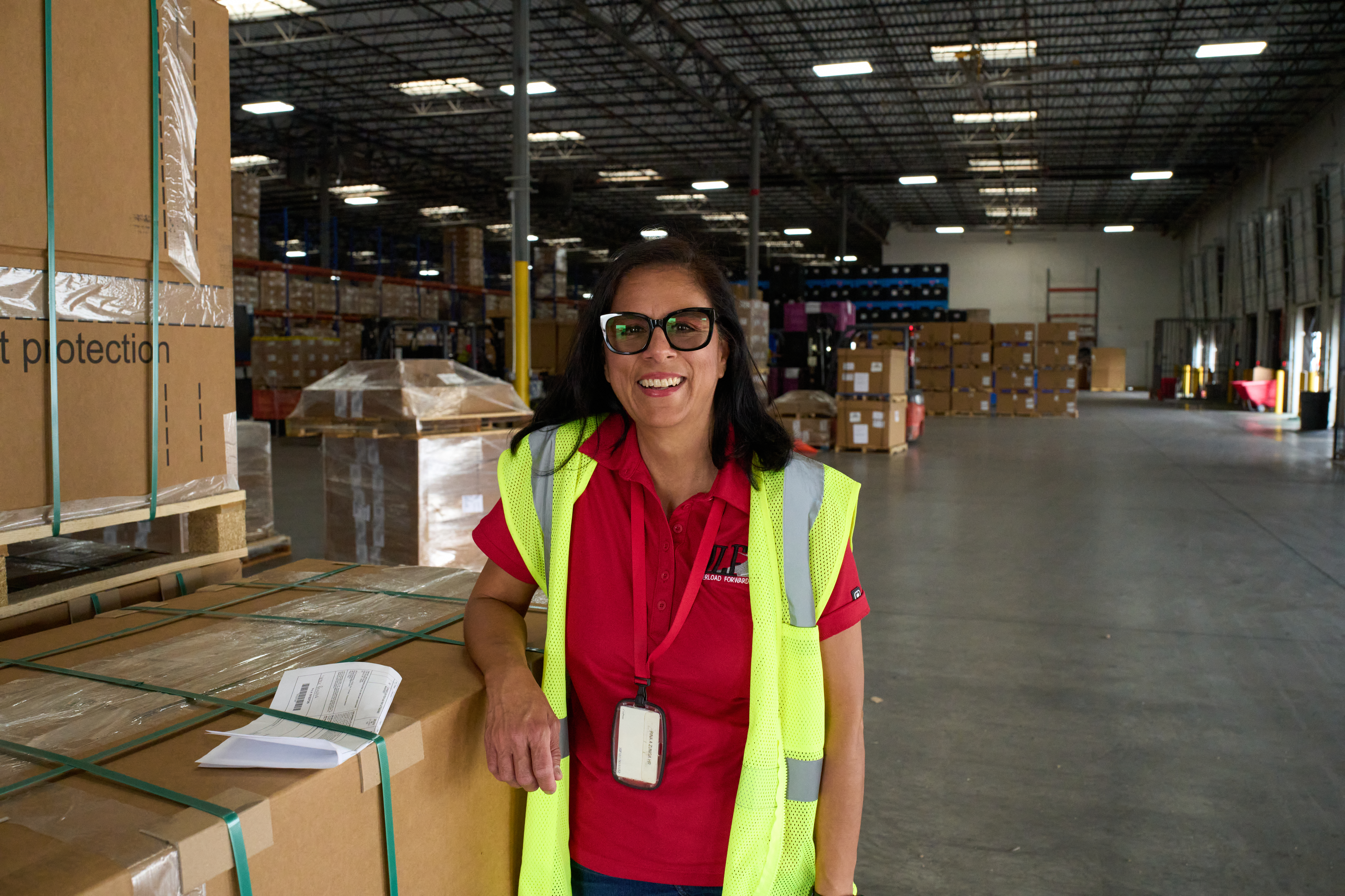 Woman leaning against a box in a warehouse.
